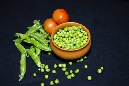 Fresh Green Peas Raw and Peeled and tomato Close-Up on Black Background studio shot