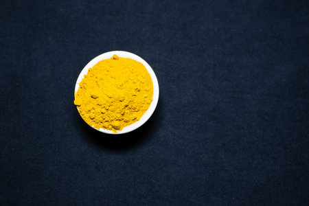 Fresh turmeric powder in ceramic bowl with black Background studio shot