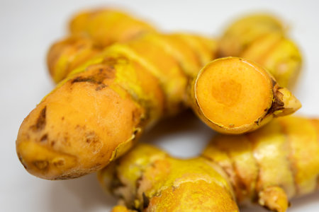 fresh raw turmeric close-up studio shot on blurred white backgroundの写真素材