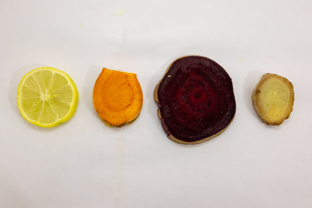 slice of fresh raw turmeric, beetroot, lemon and ginger in studio on blurred white background