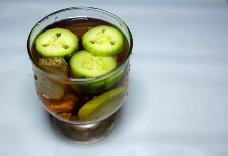 glass of water with Slices of Fresh Cucumber and other raw vegetables in studio lightの写真素材