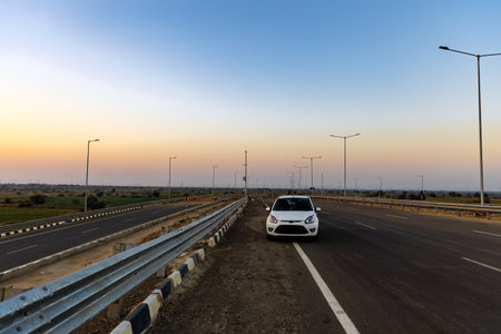isolated car standing at national highway tarmac road with dramatic sunset skyの写真素材