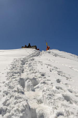 snowy trails leading to snowcap mountain summit with bright blue sky at morning image is taken at chandrashila trek summit tungnath chopta uttarakhand india.の写真素材
