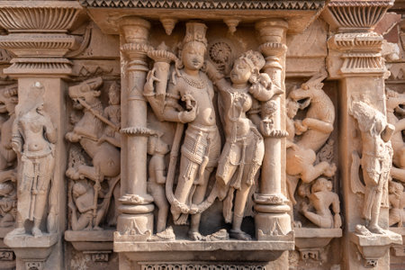 artistic carvings of hindu deities on ancient temple wall in daylightの写真素材