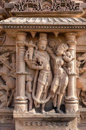 artistic carvings of hindu deities on ancient temple wall in daylightの写真素材