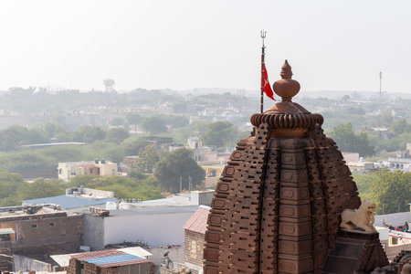 ancient hindu temple with waving holy flag and misty city background from at morning image is taken at Osiyan sacchiyay Mata Temple, jodhpur, rajasthan, India.の写真素材