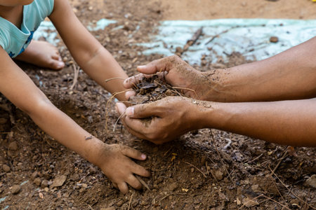 adult and child bonding while preparing clean garden soil with save earth theme at outdoorの写真素材