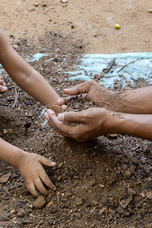 adult and child bonding while preparing clean garden soil with save earth theme at outdoorの写真素材