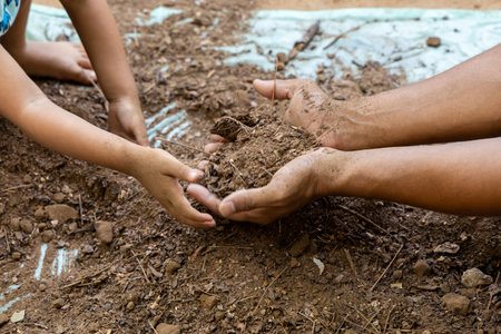adult and child bonding while preparing clean garden soil with save earth theme at outdoorの写真素材