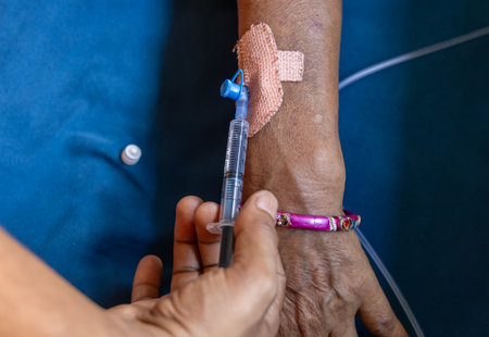 injection thorough cannula inserted in patientâs hand during daytime indoorsの写真素材