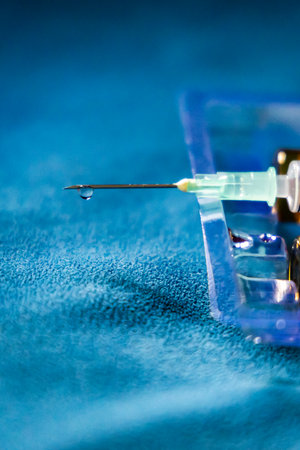 syringe with liquid medicine droplets ready to use and empty drug bottle at indoorsの写真素材
