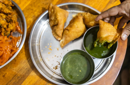 people enjoying indian traditional snack samosa with green chutney