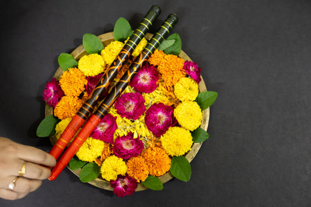 Brass puja plate adorned with marigold petals roses and dandiya sticks for festival ritual