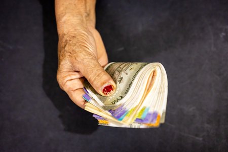 Wrinkled senior hand holding Indian rupee notes symbolizing retirement savings and security