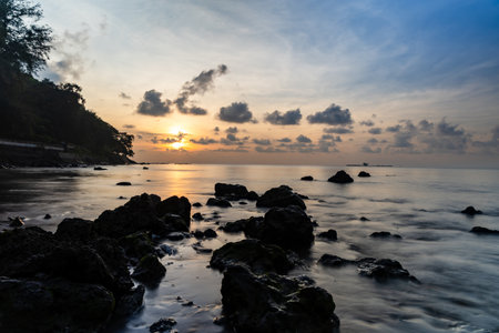 peaceful coastal landscape silhouette sunrise over calm sea and shorelineの写真素材