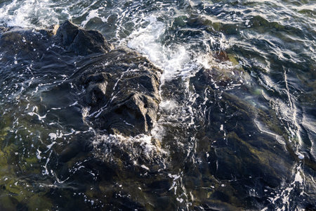ocean waves crashing on dark coastal rocks at sunset