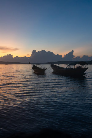 fishing boats anchored in sea backwater under golden sunset sky