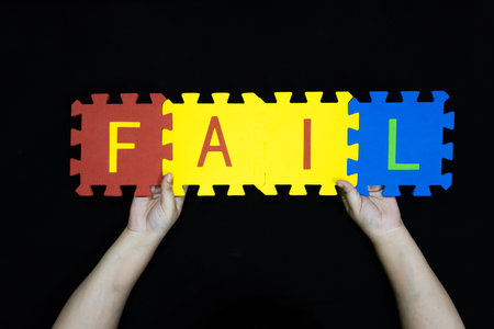 hands holding FAIL word education inspirational reminder theme against black backgroundの写真素材