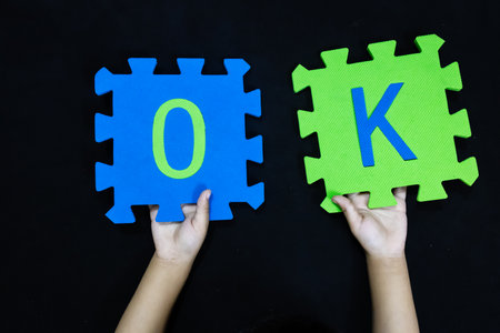 child's hands holding letter OK for message of reassurance or permission conceptの写真素材