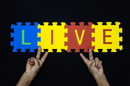 hands presenting the word live and victory sign for hope and resilience conceptの写真素材