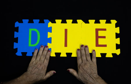 elderly hands with word die for death and end of life conceptの写真素材