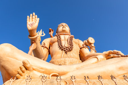 serene shiva idol with traditional attributes under clear sunny sky from low angleの写真素材