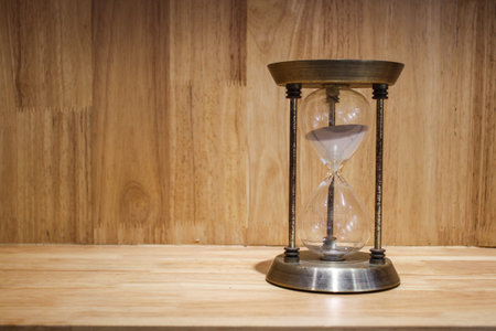 Vintage sandglass on the wooden background