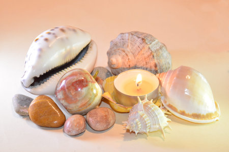 light composition of sea shells lit by candle flame combined with a pearl apple made of marbleの写真素材