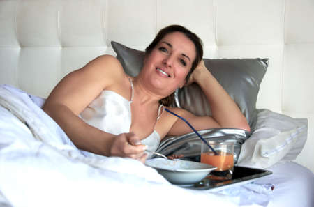 woman having breakfast in bedの写真素材