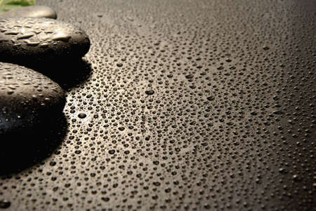 massage stones surrounded by water drops on a black backgroundの写真素材