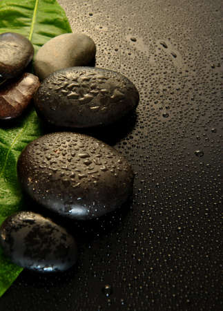 wet massage stones with green leaf and water dropsの写真素材