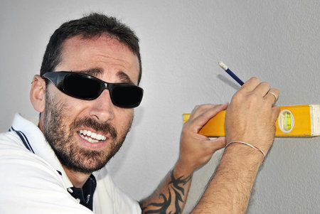 silly carpenter taking measurements on a wall