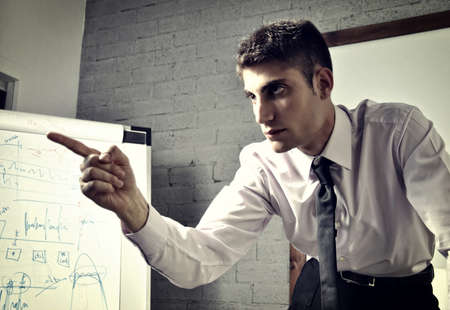 angry young businessman in his office with his hand raisedの写真素材