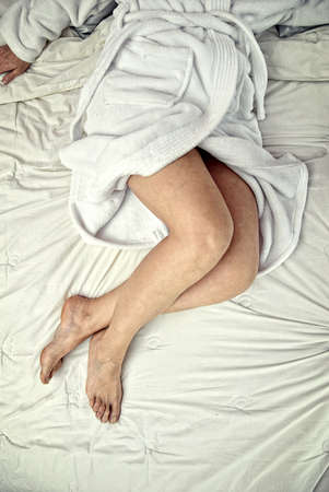 legs on a bed with white sheetsの写真素材