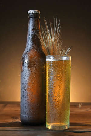 glass and bottle of cold beer on wooden tableの写真素材