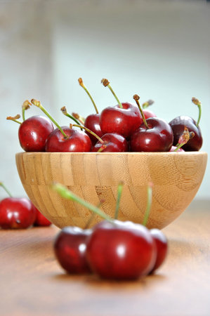 many cherries in a wooden bowl on a table