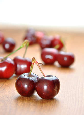 many cherries in a wooden bowl on a tableの写真素材