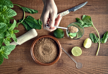 hands preparing mojito cocktail with limes and mint