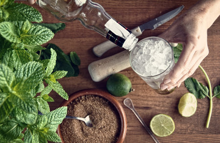 hands preparing mojito cocktail with limes and mint