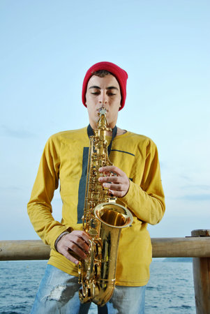 modern musician posing with his saxophone in the beach
