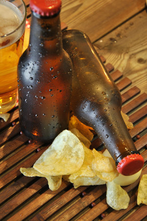 bottles of cold beer and chips on wooden tableの写真素材