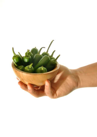 hand holding green peppers on plain backgroundの写真素材
