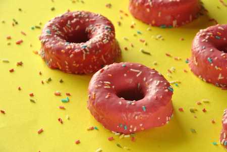 pink donuts with chocolate pieces on yellow background