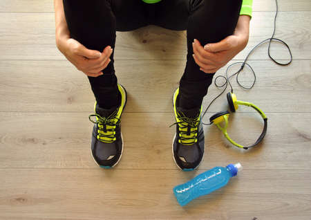 runner legs stretched on wooden floor with isotonic drinkの写真素材
