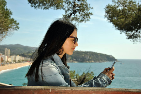Young people watching their mobile phones on the streetの写真素材