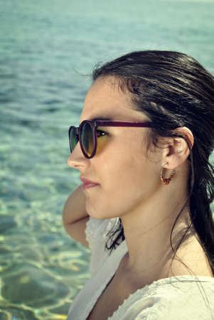 Latin woman in the seaside with hat and sunglassesの写真素材