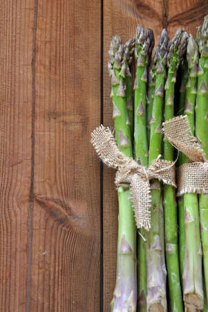 organic asparagus on wooden table accompanied by cherry tomatoes and lettuceの写真素材