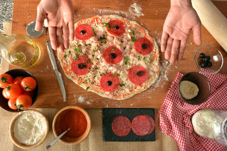 woman hands cooking pizza at home, adding all ingredientsの写真素材