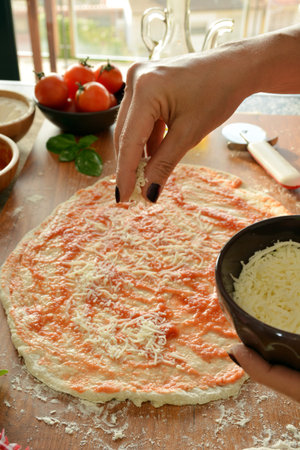 woman hands cooking pizza at home, adding all ingredientsの写真素材