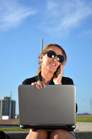 Business woman sitting on the street working with her laptopの写真素材
